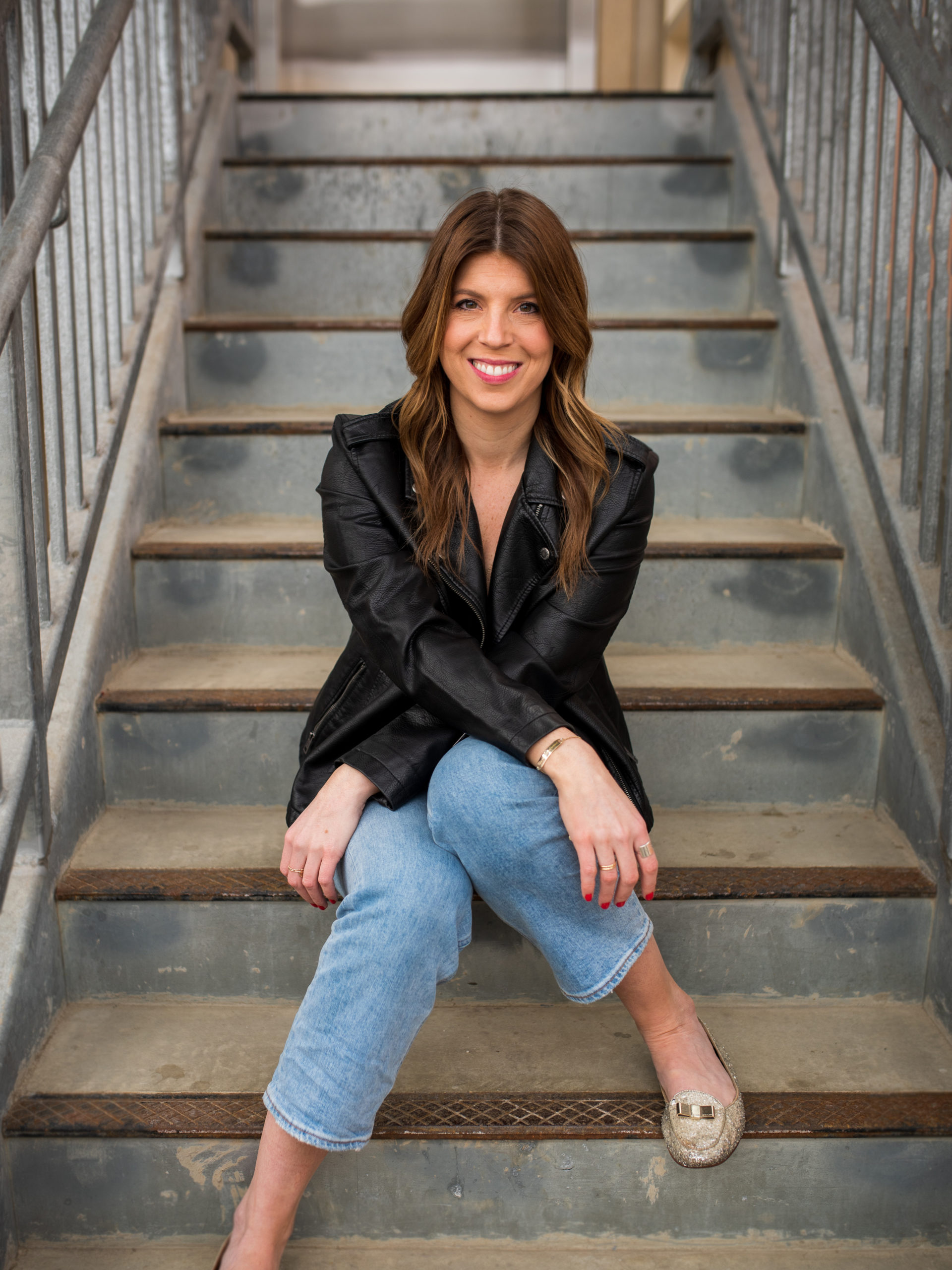 smiling woman sitting on concrete steps in a stairwell